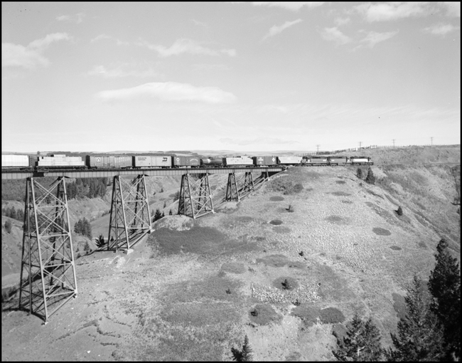 BN XE on bridge east of Glacier Park, pulled by 3 units.