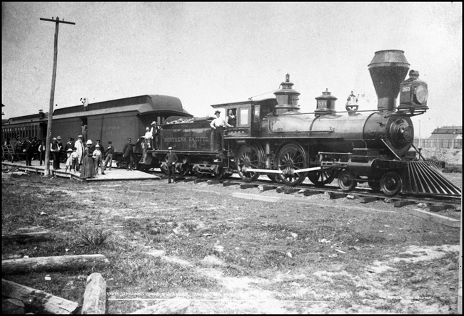 NP 350, 4-4-0 in butte with bystanders and passengers looking on. 