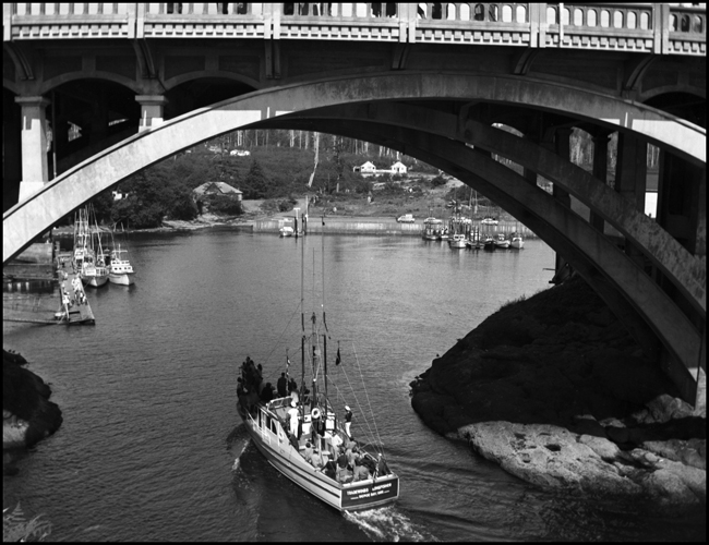 Photo is a boat passing under a bridge at Depoe Bay, OR.