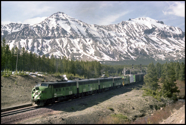 Helpers (BN 816-851-809-and 808, all F carbody units) approaching signal bridge while pushing BN X6502E west of Marias, MT.