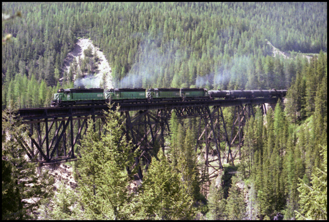 BN X6519E with BN 6519-BN 6400-BN 6431- BN 6563 on trestle bridge east of Essex, MT