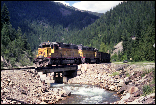 UP X2028- 2011E crossing bridge over stream between Burke and Wallace, ID.
