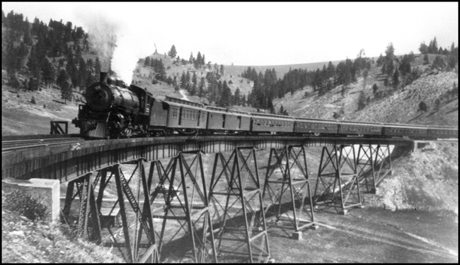 One of the mainline through passenger trains heads west with a  Q-4 Pacific.  It must be summer because the windows are open on some of the passenger cars,