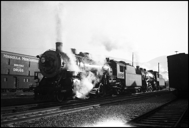 A W-3 Mikado and a Q-5 Pacific run from the engine terminal to their work assignment, which may be two separate trains or a doubleheaded passenger movement.  The Mikado is a 1920 ALCO, serial number 62460.  It will be scrapped January 1955.