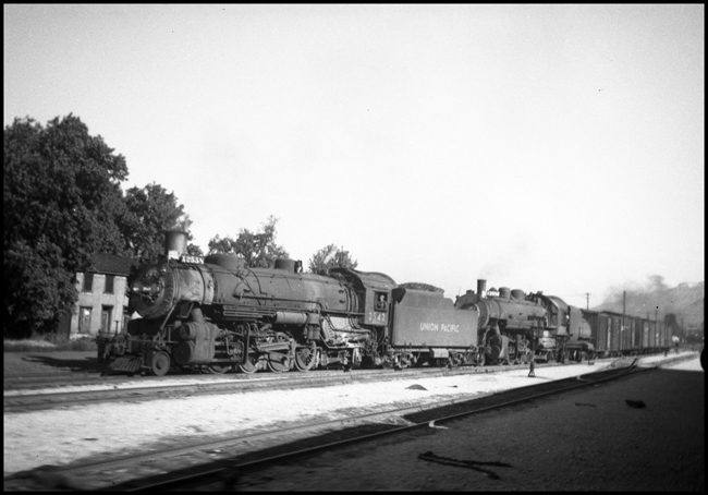 A Mikado and a Pacific are making a diverging move at an unknown location on the northern edges of the Union Pacific.  It is an unusual combination of power, and probably means that one of the engines is being relocated to an area of greater need.