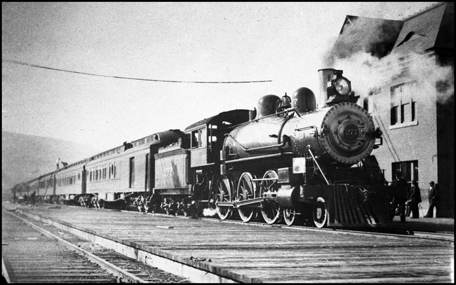 NP 277, Class P steam locomotive stopped at early depot in Livingston with passenger train.  Depot in picture was on the north side of the tracks across the yard from the depot that was used at time of the BN merger.  Passenger train in photo was being serviced.