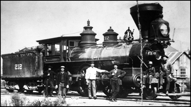 NP 212, 4-4-0 locomotive OS at Heron, MT, with railroaders standing around in photo.