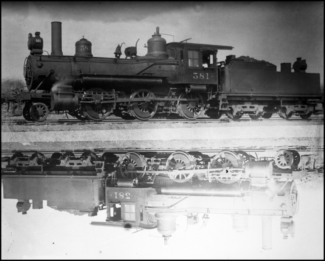 NP 581, Class D locomotive, with mirror reflection in water in front of locomotive. Former locomotive number 318.