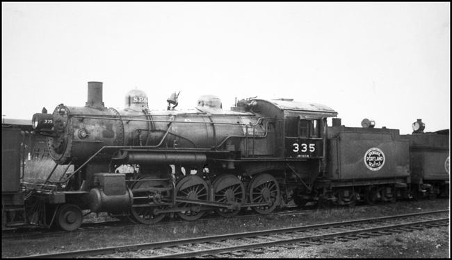 SP&S 335, 2-8-0 locomotive between other steam locomotives on storage track at Vancouver, WA.