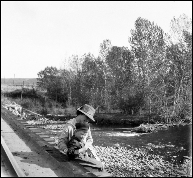 Merle Levy caring for Ron Nixon as they sit on the edge of a railroad bridge in Roberts, MT