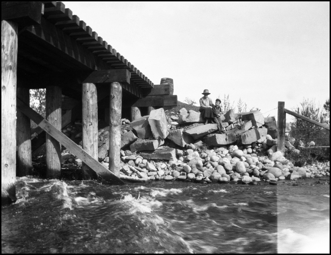 Merle Levy caring for Ron Nixon as they sit on the edge of a railroad bridge in Roberts, MT