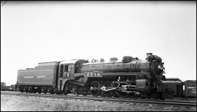 CPR 2710, 4-6-2 locomotive standing near service shop as outbuilding are visible in back of locomotive. 