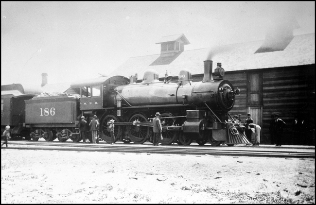 Very early photograph of passenger train in Missoula.  Note the log Depot.  Train was being handled by NP 186, Class Rc, 4-6-0 locomotive. 