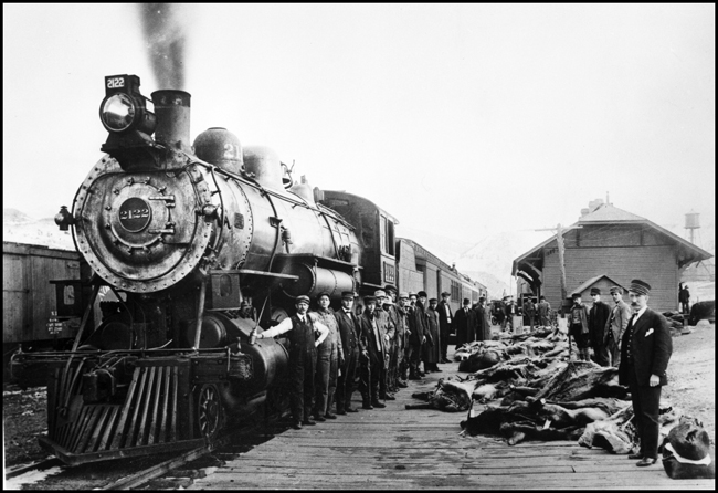 NP 2122, Class Q-3 on Park Train at Gardiner, with crew and several hunters on depot platform with the elk they have taken on their successful hunting trip.