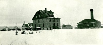 Taylor Hall, greenhouses and heating plant in the snow, 1906