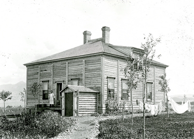 A man standing on the porch of a Farm Dwelling, 1896