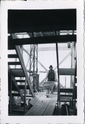 A man wheeling a wheelbarrow into the construction of MSC Library, 1949