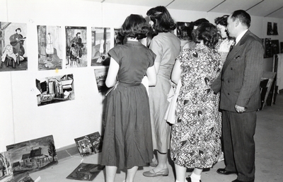A group of people observe paintings in a show.