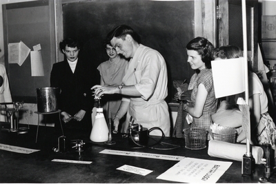 A group of students watch a professor conduct an experiment.