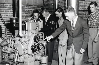 A group of students examining a motor of some kind.