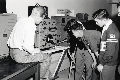 A group of students observe some type of electronic machine
