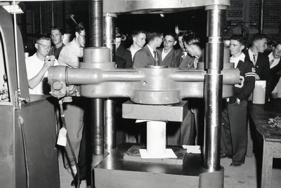 A group of students gather around to examine a piece of machinery