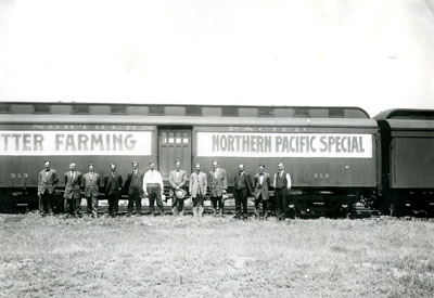 Group of people standing in front of the Better Farming Northern Pacific Special train.