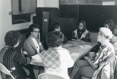 Women sitting around a table at Focus on Women, 1976