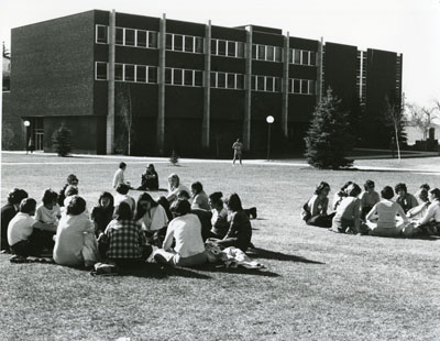 Two groups of people sitting on the lawn at the Women Aware Conference, 1976
