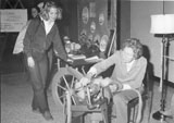 Two women, one sitting at a spinning wheel at the Women Aware Conference