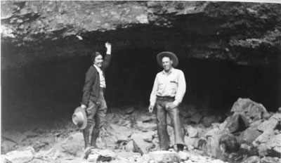 Harriette Cushman and an unidentified man posing in front of a cave