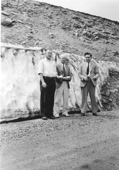 Three men standing in front of a snow bank