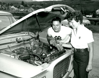 Dale Webster Watches Eileen Dutton as she Checks the Water Level in the Radiator of Her Car