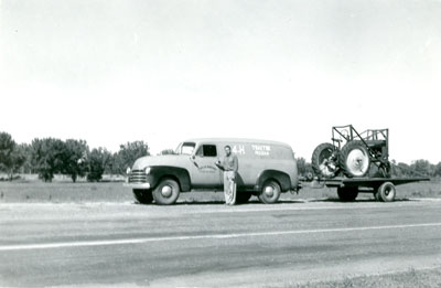 A Man Standing in Front of the 4-H Tractor Program Truck, Hauling a Tractor