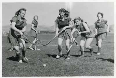 Women playing field hockey