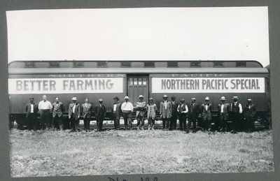Group of men standing in front of the Better Farming Northern Pacific Special train, 1910