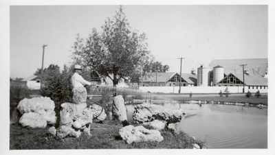 Man sprinkling water into a pond at Harrington Park, Montana Experiment Station