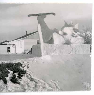Snow sculpture of a crowned figure reclining with an upraised ski