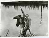 Men standing on a dock near water, 1920s