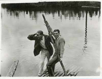 Men standing on a dock near water, 1920s