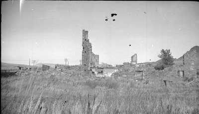 A collapsed stone building with the chimney standing