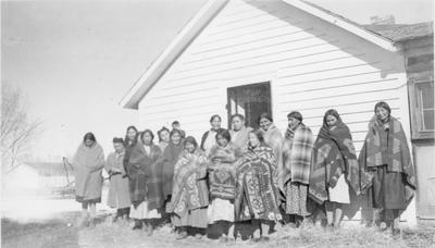 Group of Arapaho Women Standing in Front of a Wooden Building