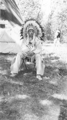 Bernadotte: Blackfeet Indians: Man in Full Indian Dress Sitting on a Metal Folding Chair, 1939