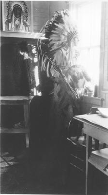 Photo of a man in full dress looking out a window, Browning, Montana