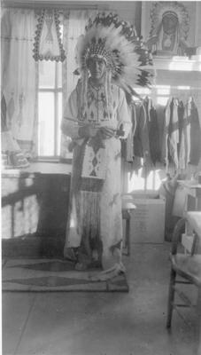 Photo of a young man in ceremonial dress holding a peace pipe