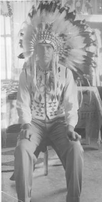Photo of a young man wearing a head dress, Browning, Montana, 1933