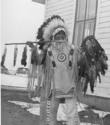 Photo of a young man posing with a spear and feather ring, Browning, Montana