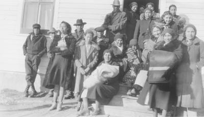 Large Group of Indian Men and Women Dressed Warmly Gathered Around Steps, Browning, Montana