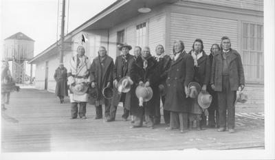Black and white photo of a group of men outside of the train depot, waiting for a train to Hollywood.