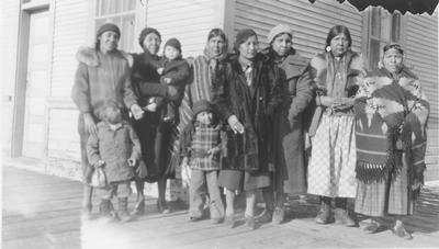 Black and white photo of a group of women and children outside the train depot.